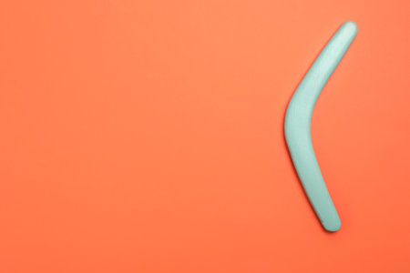 Turquoise boomerang on orange background, top view. Space for textの写真素材