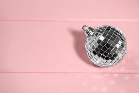 Shiny disco ball on pink wooden background, above view. Space for textの写真素材