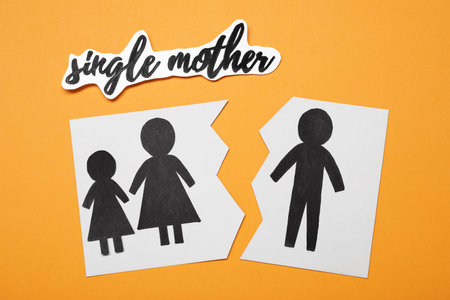Being single mother after divorce concept. Paper cutouts demonstrating broken family on orange...
