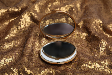 Bright cosmetic pocket mirror on gold fabricの写真素材