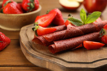 Delicious fruit leather rolls and strawberries on wooden table, closeupの写真素材