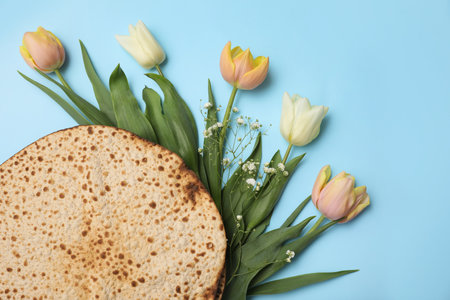 Tasty matzos and fresh flowers on light blue background, flat lay. Passover (Pesach) celebrationの写真素材