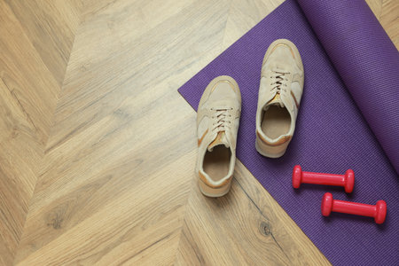 Dumbbells, sneakers and mat on wooden floor, above view. Space for textの写真素材