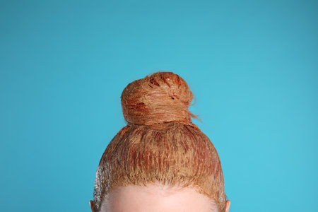 Young woman dyeing her hair with henna on light blue background, closeupの写真素材
