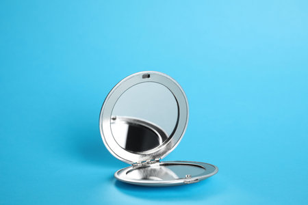 Stylish cosmetic pocket mirror on light blue backgroundの写真素材