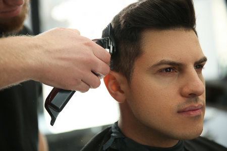 Professional barber making stylish haircut in salon, closeupの写真素材
