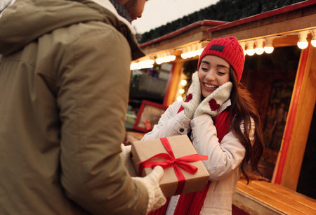 Lovely couple with Christmas present at winter fairの写真素材