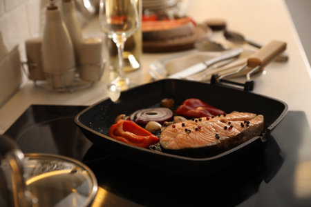 Frying pan with tasty salmon steak and vegetables on stoveの写真素材