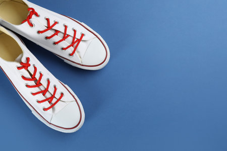 Pair of trendy sneakers on blue background, flat lay. Space for textの写真素材