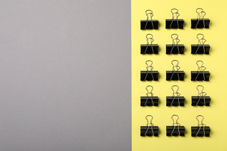 Black binder clips on color background, flat lay. Space for textの写真素材