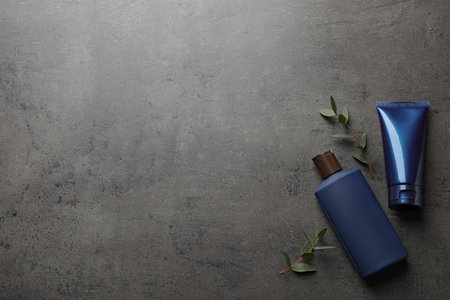 Men's facial cream, shampoo and green leaves on gray stone table, flat lay. Mockup for designの写真素材