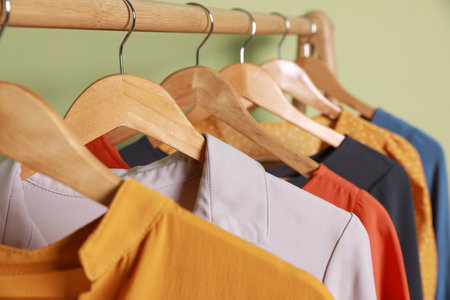 Collection of trendy women's garments on rack near green wall, closeup. clothing rental serviceの写真素材
