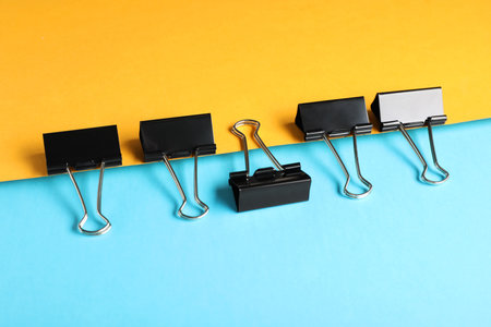 Black binder clips on color background. stationery itemsの写真素材