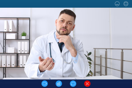 Pediatrician consulting patient online using video chat in clinic, view from webcamの写真素材