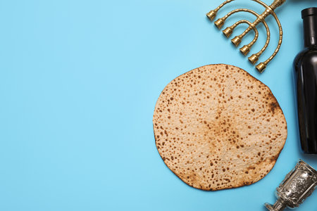 Tasty matzo, wine and menorah on light blue background, flat lay with space for text. Passover...