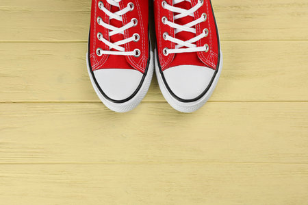 Pair of red sneakers on yellow wooden table, flat lay. Space for textの写真素材