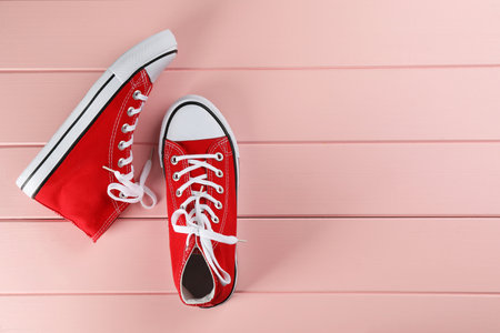 Pair of red sneakers on pink wooden table, flat lay. Space for textの写真素材