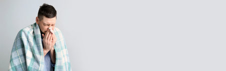 Man with plaid suffering from runny nose on light backgroundの写真素材