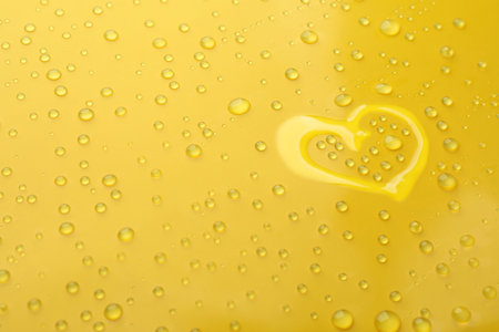 heart shape of water and drops on yellow backgroundの写真素材