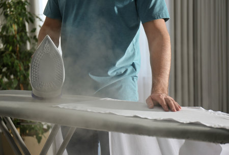 Man ironing clean shirt at home, closeupの写真素材