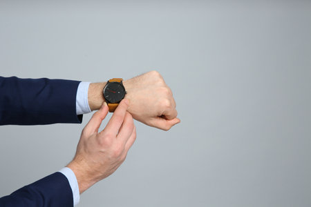 Closeup view of businessman wearing wristwatch against gray background, space for text. time managementの写真素材