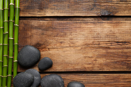 Spa stones and bamboo stems on wooden table, flat lay. Space for textの写真素材