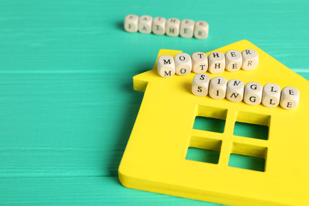 House model and cubes with text Single Mother on turquoise wooden table, closeupの写真素材