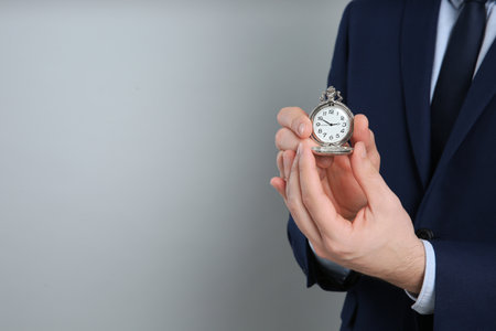 Closeup view of businessman holding pocket watch on gray background, space for text. time managementの写真素材