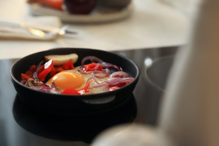 Frying pan with tasty egg and vegetables on stoveの写真素材