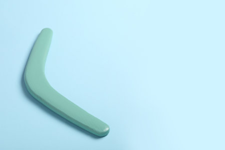 Wooden boomerang on light blue background. Space for textの写真素材