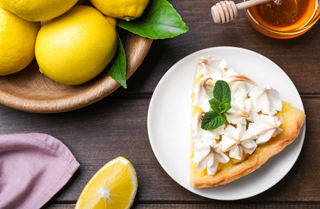 Piece of delicious lemon meringue pie with mint on wooden table, flat layの写真素材