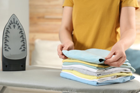 Woman with folded clothes after ironing near board at home, closeupの写真素材