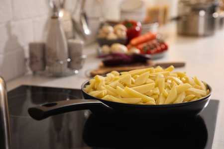 Frying pan with cut raw potatoes on cooktopの写真素材