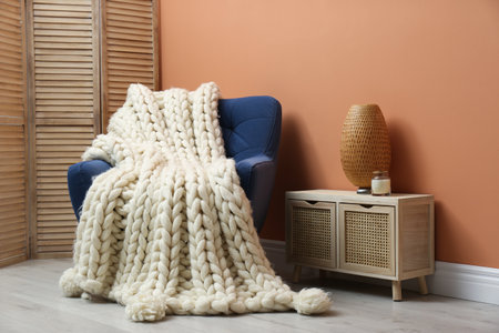 Knitted merino wool plaid on armchair in roomの写真素材