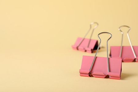 Binder clips on beige background, closeup. Space for textの写真素材