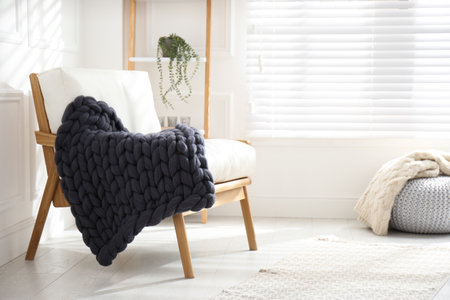 Knitted merino wool plaid on armchair in room. Space for textの写真素材