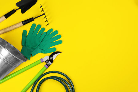 Flat lay composition with gardening tools on yellow background, space for textの写真素材