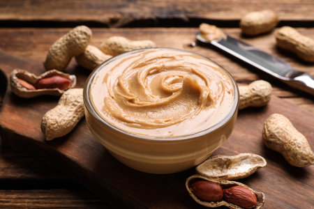 Yummy peanut butter in glass bowl on wooden table, closeupの写真素材