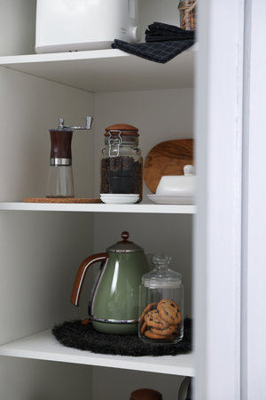 Manual coffee grinder and other appliances on shelving unit in kitchenの写真素材