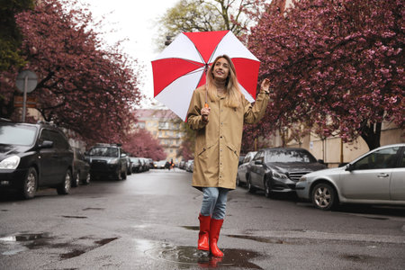 Young woman with umbrella walking on spring dayの写真素材