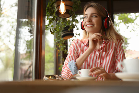 Young woman with headphones listening to music in cafeの写真素材