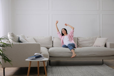 Woman resting on sofa in living roomの写真素材