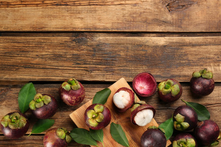 Fresh ripe mangosteen fruits on wooden table, flat lay. Space for textの写真素材