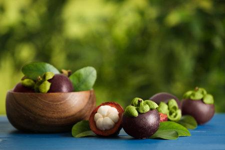 Delicious ripe mangosteen fruits on blue wooden table outdoors, space for textの写真素材
