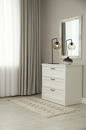 Hallway with stylish chest of drawers and mirror. interior design