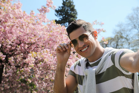 Happy handsome man taking selfie in parkの写真素材