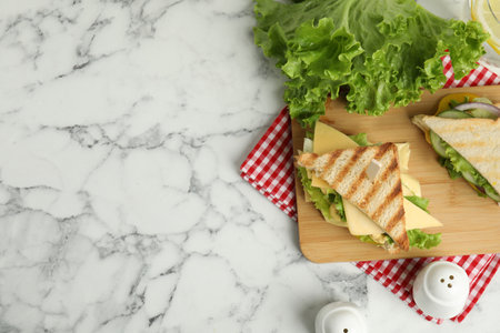 Wooden board with tasty sandwiches on white marble table, flat lay. Space for textの写真素材