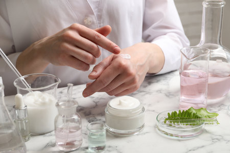 Scientist testing cosmetic product at white marble table in laboratory, closeupの写真素材