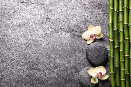 Spa stones, beautiful orchid flowers and bamboo stems on gray table, flat lay. Space for textの写真素材
