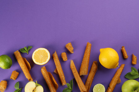 Flat lay composition with delicious fruit leather rolls on purple background. Space for textの写真素材